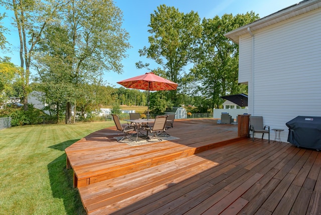 wooden deck featuring a lawn, grilling area, and a storage unit