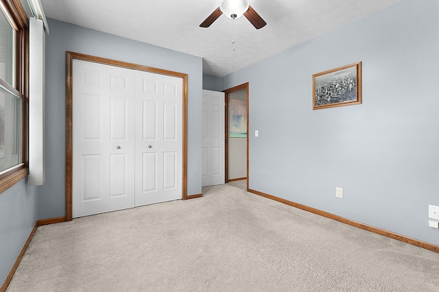 unfurnished bedroom with ceiling fan, light colored carpet, and a closet