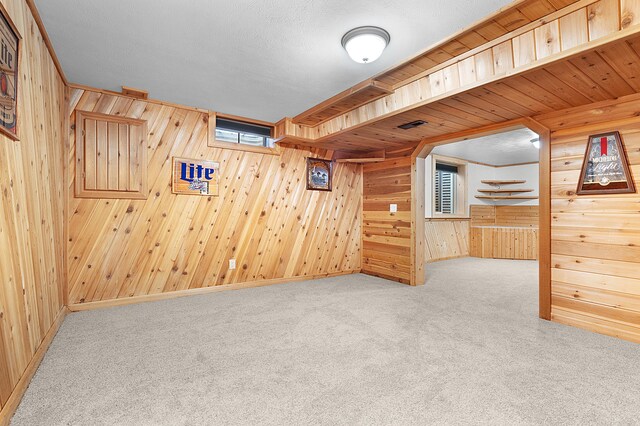 unfurnished room with light colored carpet and wooden walls