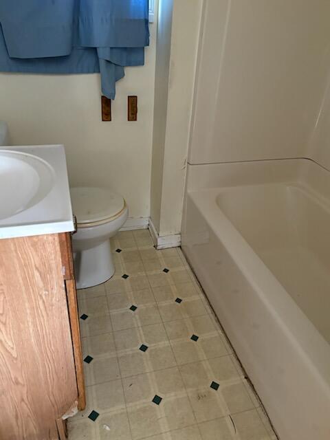 bathroom featuring vanity, toilet, tile patterned floors, and a tub