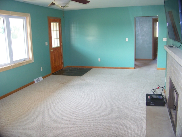 interior space with carpet, ceiling fan, and a brick fireplace