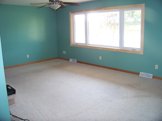 carpeted spare room with a wealth of natural light and ceiling fan