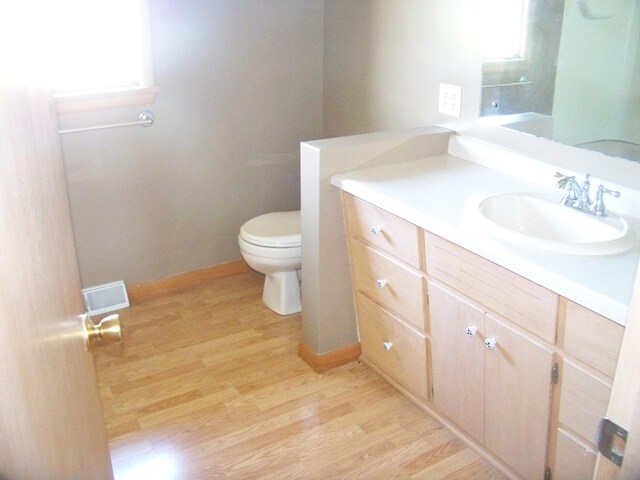 bathroom featuring toilet, plenty of natural light, hardwood / wood-style flooring, and vanity