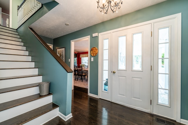 entrance foyer with dark hardwood / wood-style floors, a chandelier, and a textured ceiling