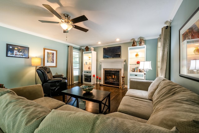 living room with dark wood-type flooring, ornamental molding, a high end fireplace, and ceiling fan