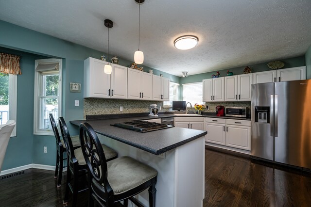 kitchen with pendant lighting, white cabinets, and appliances with stainless steel finishes