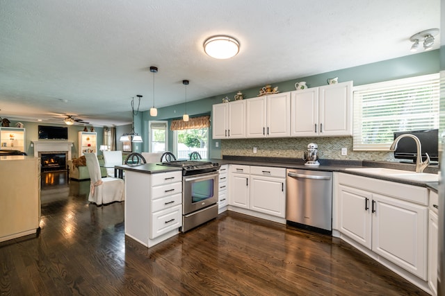 kitchen featuring stainless steel appliances, white cabinets, dark hardwood / wood-style flooring, kitchen peninsula, and decorative light fixtures