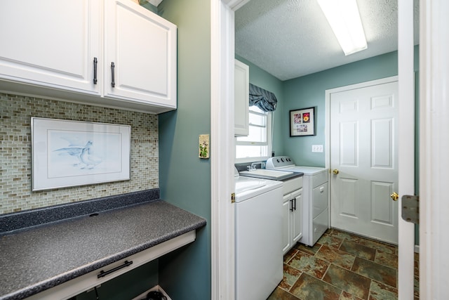 washroom with a textured ceiling, washer and clothes dryer, and cabinets