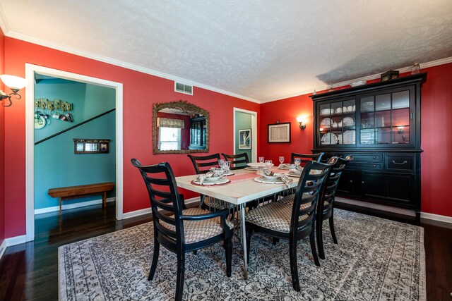 dining area with dark wood-type flooring, crown molding, and a textured ceiling