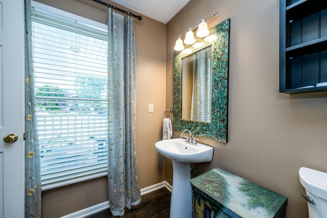 bathroom with hardwood / wood-style flooring, a healthy amount of sunlight, toilet, and a textured ceiling