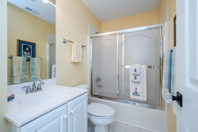 full bathroom with bath / shower combo with glass door, tile patterned floors, vanity, and toilet