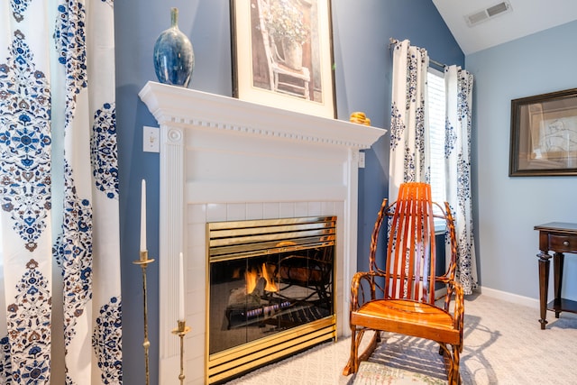 living area featuring a tile fireplace, vaulted ceiling, and carpet