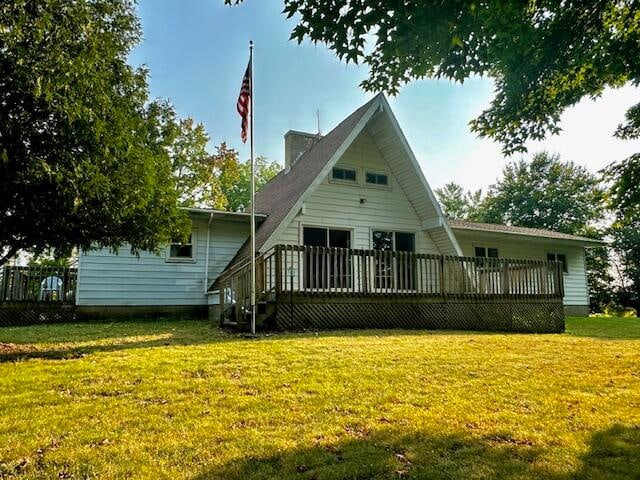 rear view of house featuring a lawn and a deck