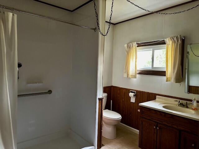 bathroom with vanity, toilet, a shower with shower curtain, and wood walls