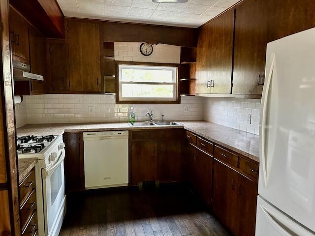 kitchen featuring backsplash, sink, white appliances, and dark hardwood / wood-style flooring