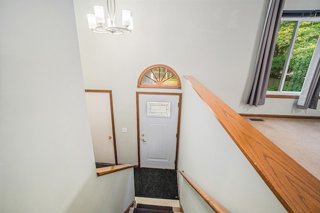 doorway to outside with a wealth of natural light, light colored carpet, and a notable chandelier