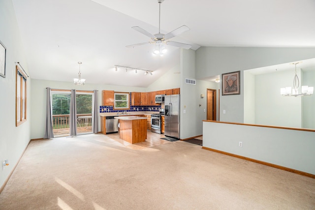 kitchen with ceiling fan with notable chandelier, appliances with stainless steel finishes, decorative light fixtures, and a center island