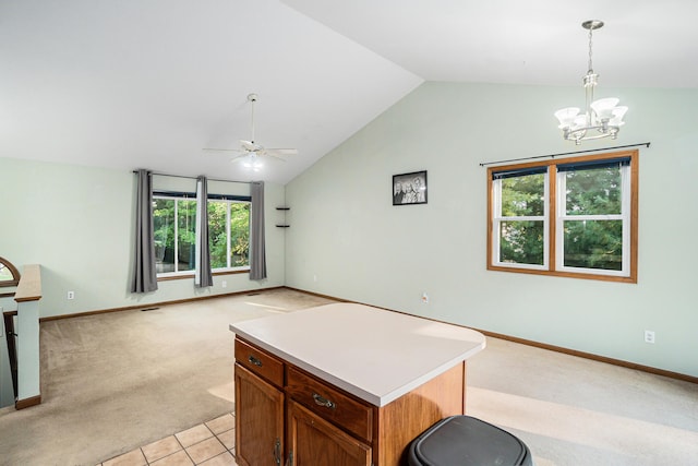 kitchen featuring ceiling fan with notable chandelier, decorative light fixtures, a kitchen island, vaulted ceiling, and light colored carpet