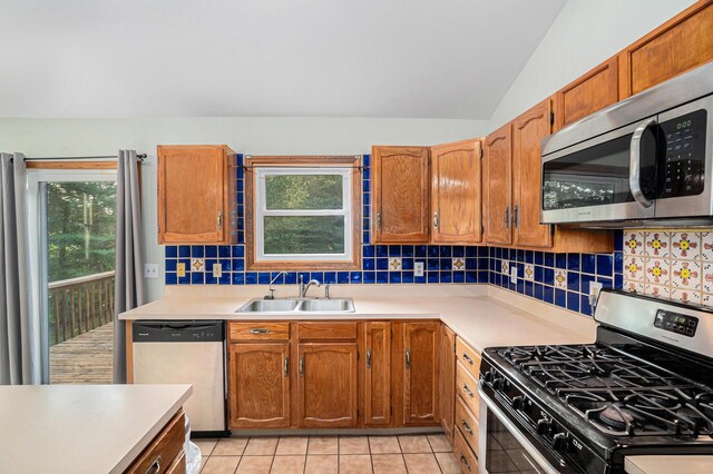 kitchen with tasteful backsplash, stainless steel appliances, sink, vaulted ceiling, and light tile patterned flooring