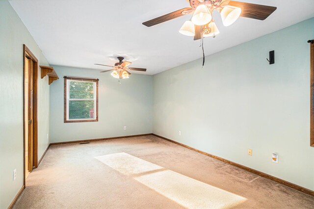 spare room with ceiling fan and light carpet