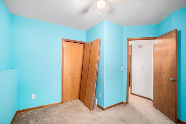 unfurnished bedroom with light colored carpet, ceiling fan, and a closet