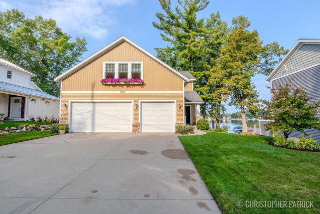 view of front of house featuring a garage, a water view, and a front lawn