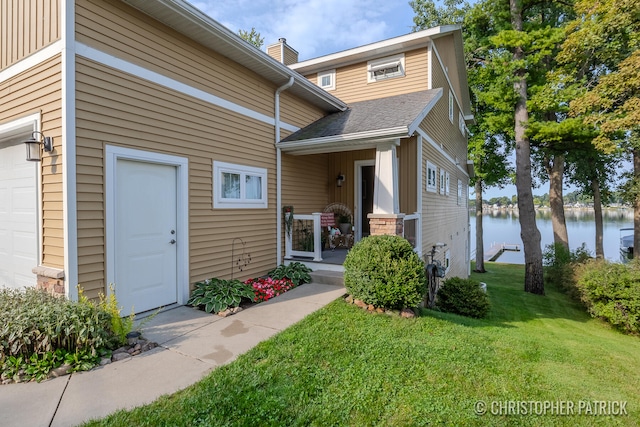 doorway to property featuring a garage, a water view, and a yard