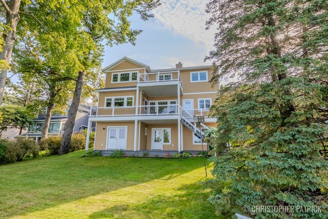 back of house with a balcony and a lawn