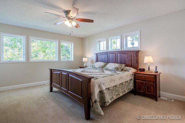 carpeted bedroom featuring multiple windows and ceiling fan