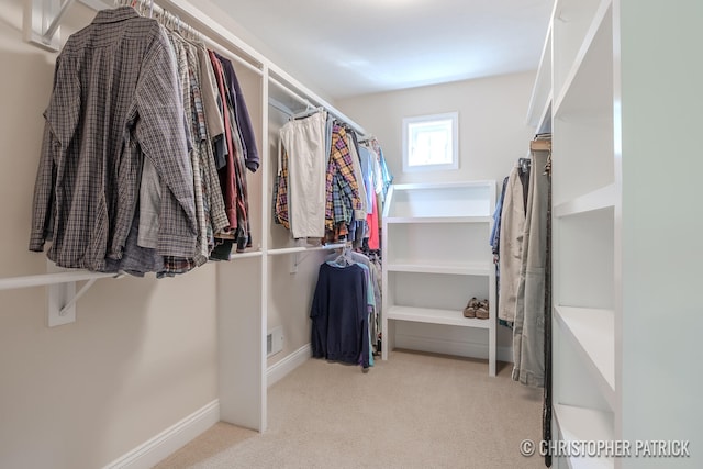 walk in closet with light carpet