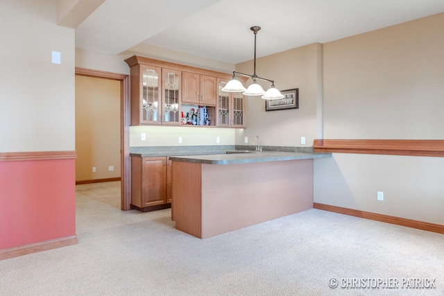 kitchen featuring pendant lighting, kitchen peninsula, sink, and light colored carpet