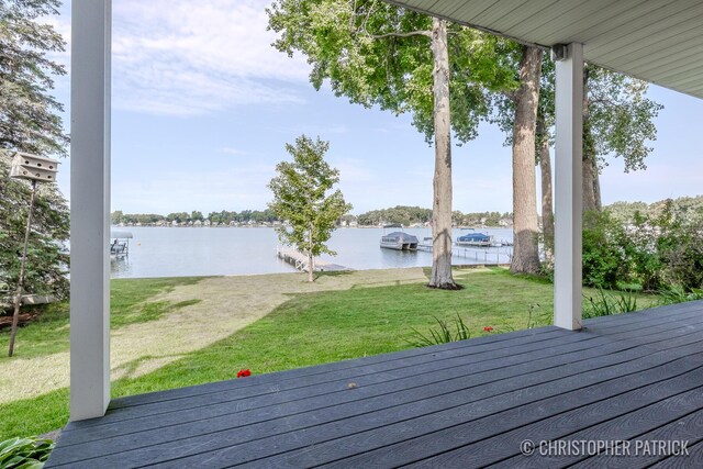 wooden deck with a water view and a lawn