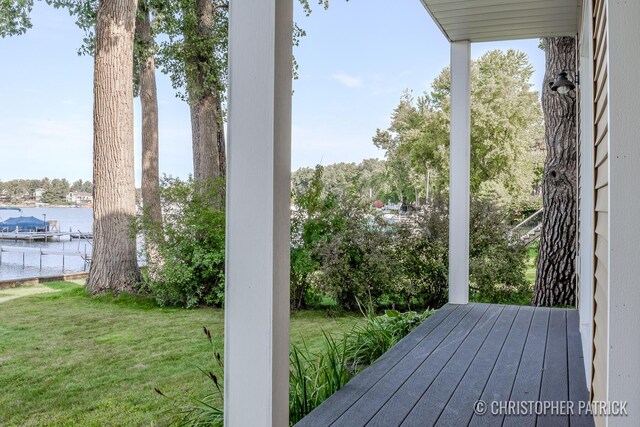 wooden terrace with a water view and a lawn