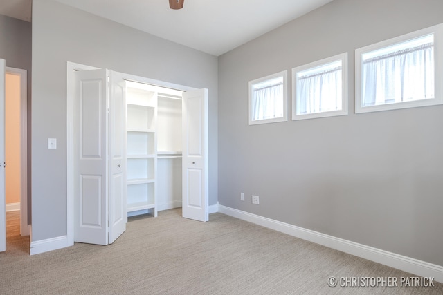 unfurnished bedroom with ceiling fan, light colored carpet, and a closet