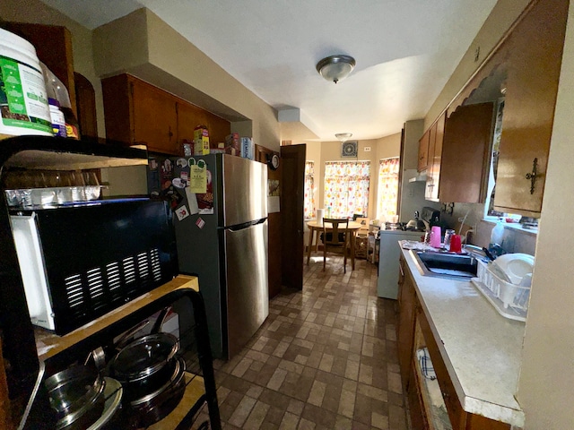 kitchen featuring stainless steel refrigerator, sink, and range