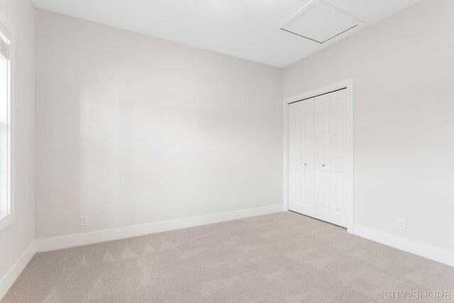 unfurnished bedroom featuring light carpet and a closet