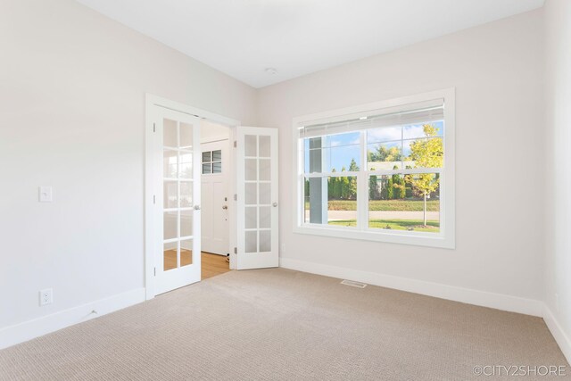 empty room featuring french doors and light colored carpet