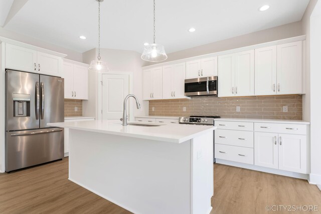 kitchen featuring white cabinets, stainless steel appliances, and an island with sink