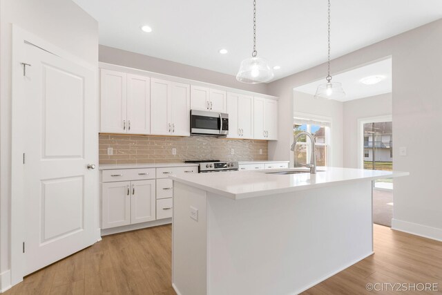 kitchen with white cabinetry, sink, light hardwood / wood-style floors, a kitchen island with sink, and appliances with stainless steel finishes