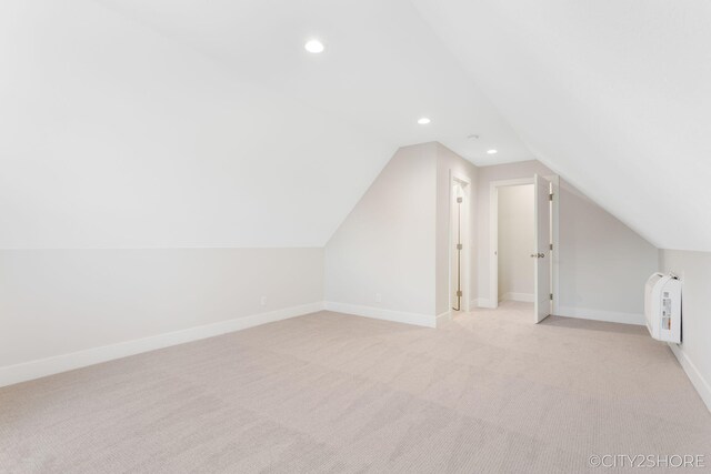 additional living space featuring light carpet and vaulted ceiling