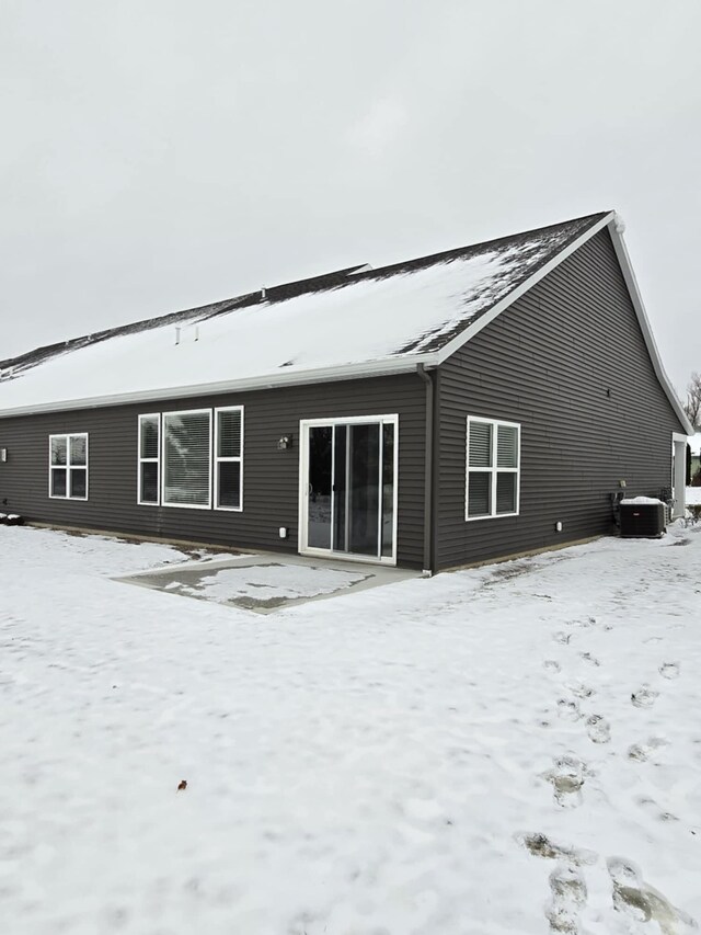 snow covered house featuring central AC unit