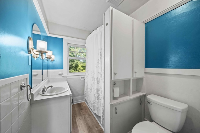 bathroom featuring toilet, hardwood / wood-style floors, a notable chandelier, vanity, and tile walls