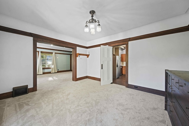 spare room featuring a chandelier and light colored carpet