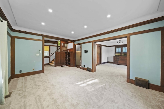 carpeted empty room featuring an inviting chandelier and crown molding