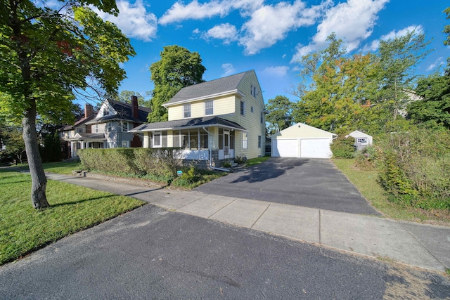 view of front of home featuring a garage, a porch, a front lawn, and an outdoor structure