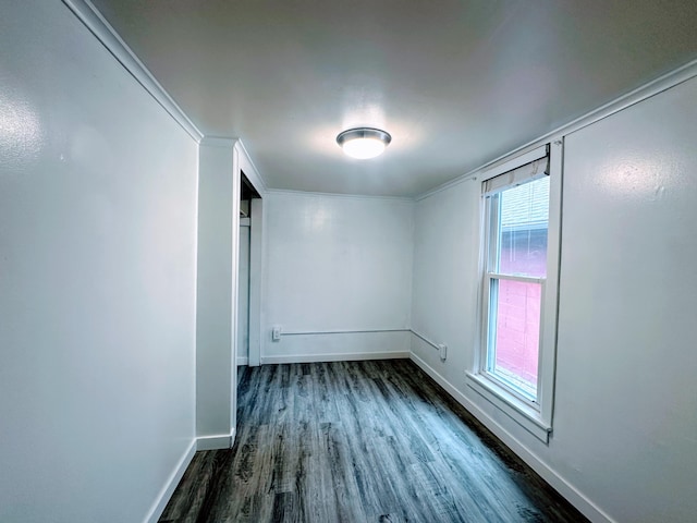 spare room featuring crown molding and dark wood-type flooring