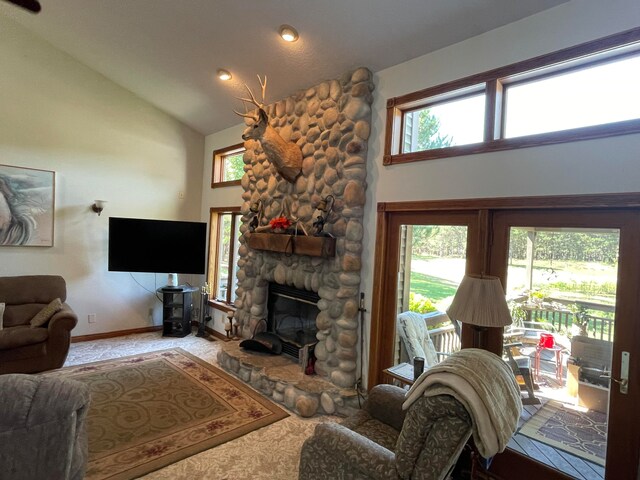 living room featuring carpet floors, a stone fireplace, and plenty of natural light