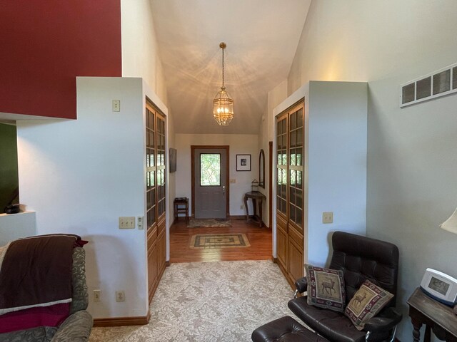 foyer entrance with lofted ceiling, an inviting chandelier, and light hardwood / wood-style flooring