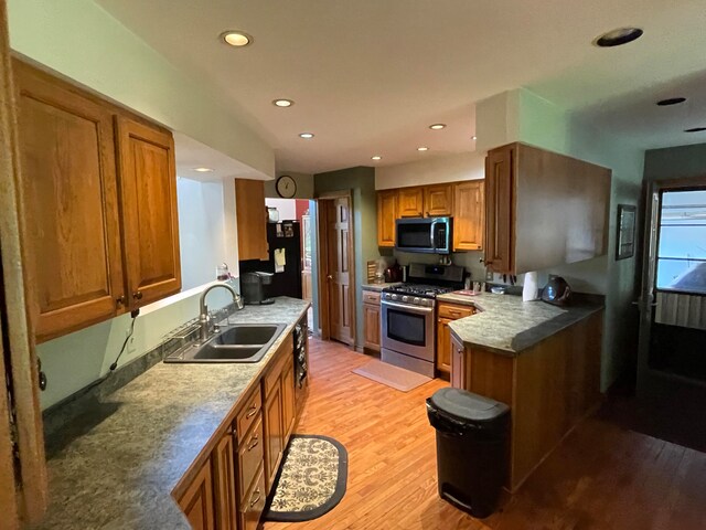 kitchen featuring light hardwood / wood-style floors, appliances with stainless steel finishes, sink, and kitchen peninsula