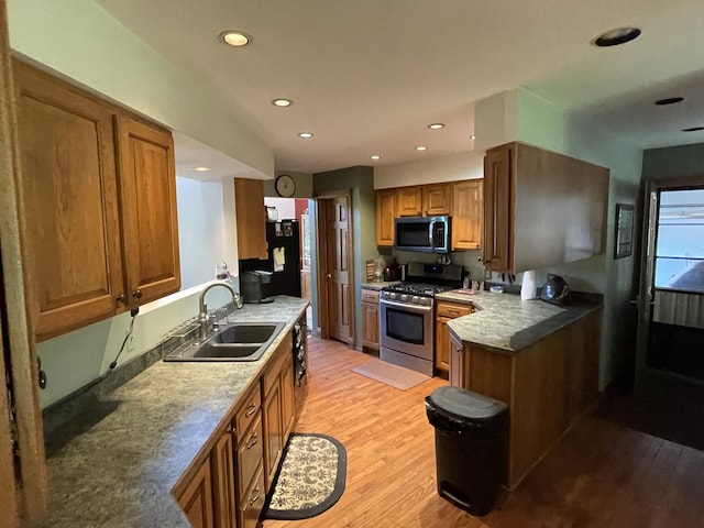 2622 S Sheridan Rd, Caro, MI 48723 - kitchen featuring a sink, light wood finished floors, a peninsula, brown cabinetry, and stainless steel range with gas cooktop